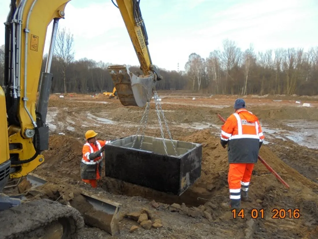 Trunk chamber being lowered into the trench by excavator