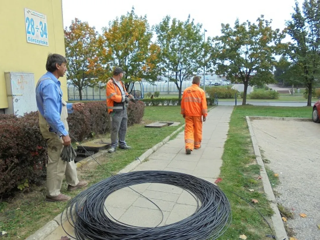 Coil of fibre-optic cable on a verge beside the pavement, crew in the background