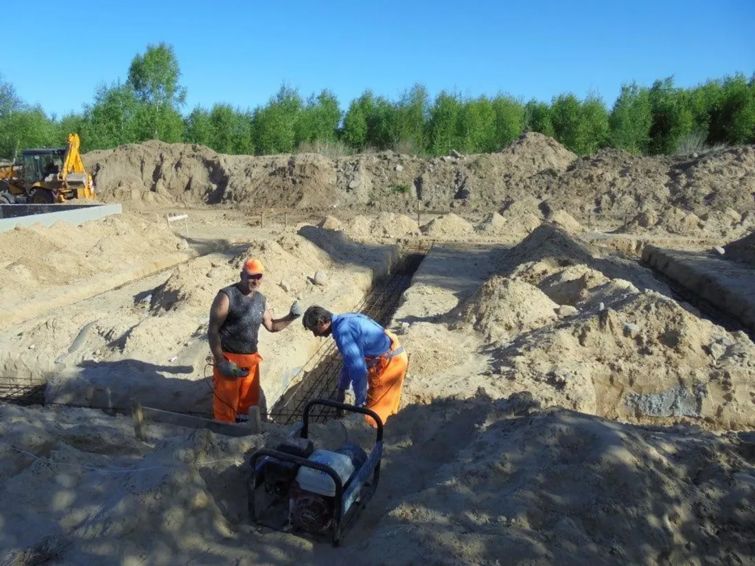 Operatives with a plate compactor in a foundation trench