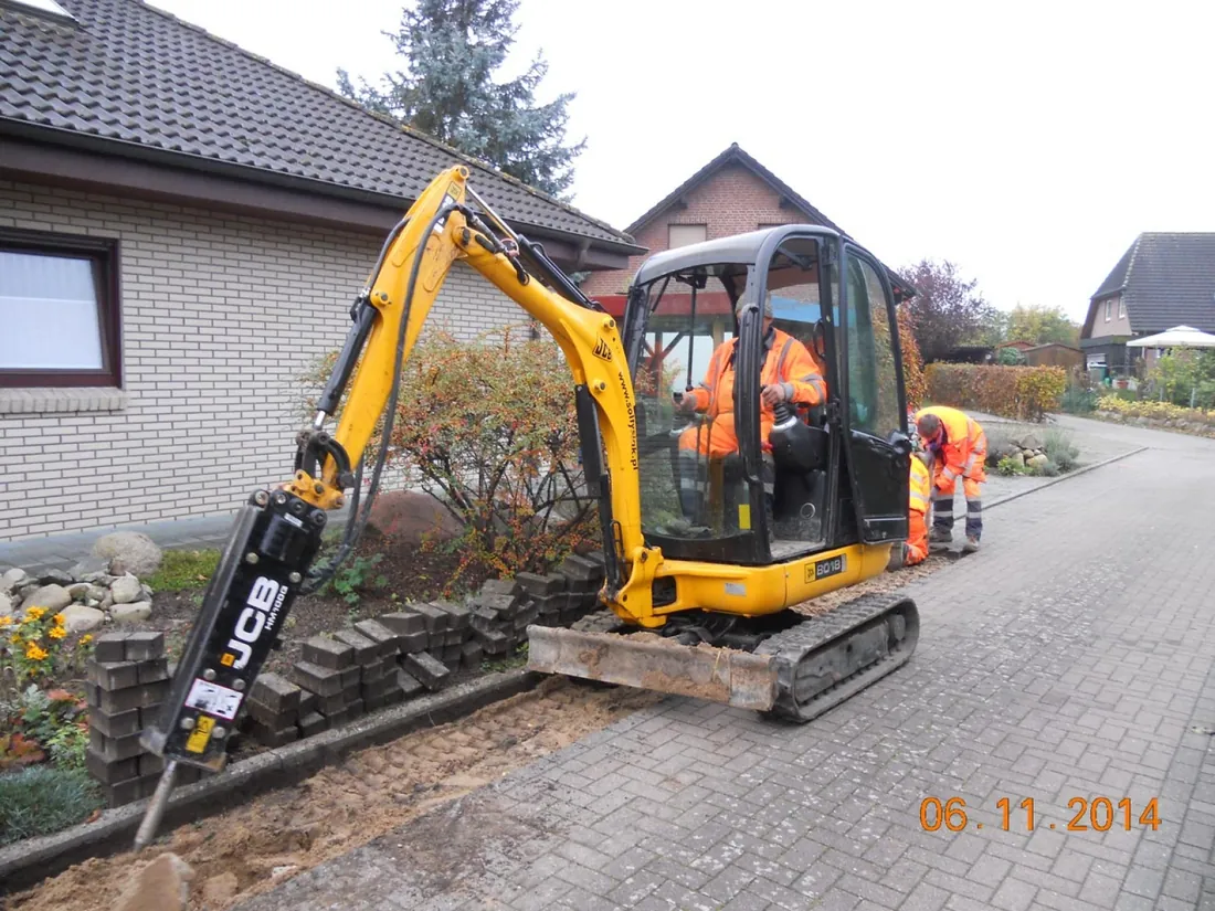 Excavator with a hydraulic breaker breaking up the footway sub-base