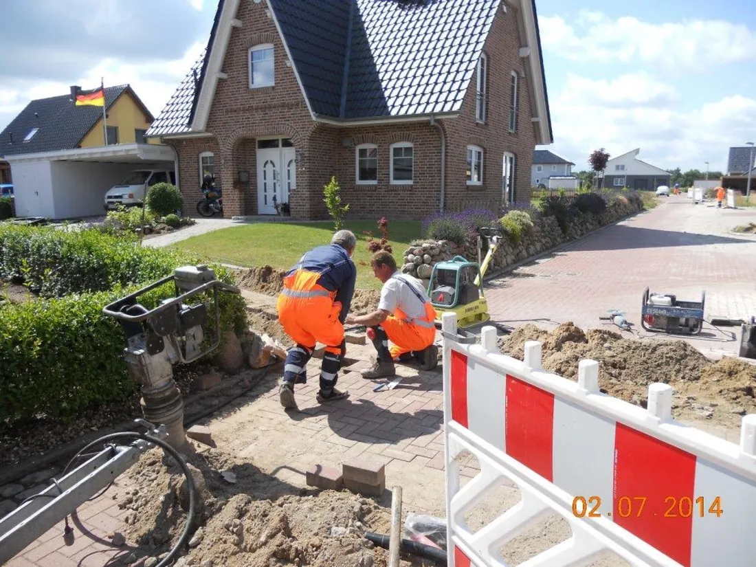 Operatives reinstating block paving outside a house