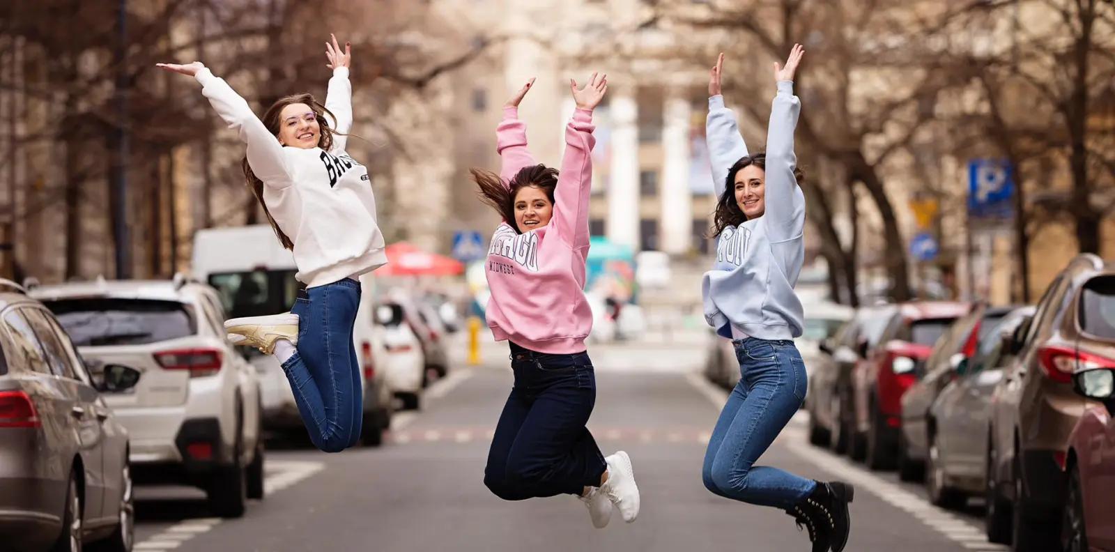 Joyful young women jumping in the air on a city street