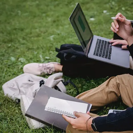 Students studying with a laptop on the grass