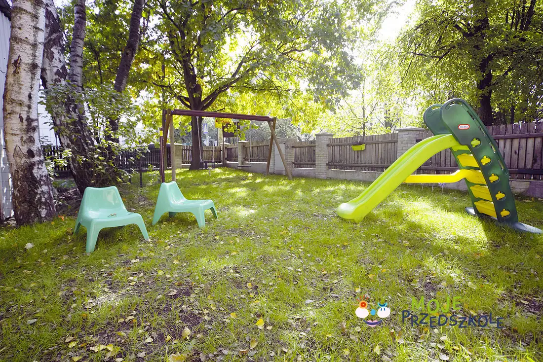 Preschool garden: a slide, swings and small chairs among the trees