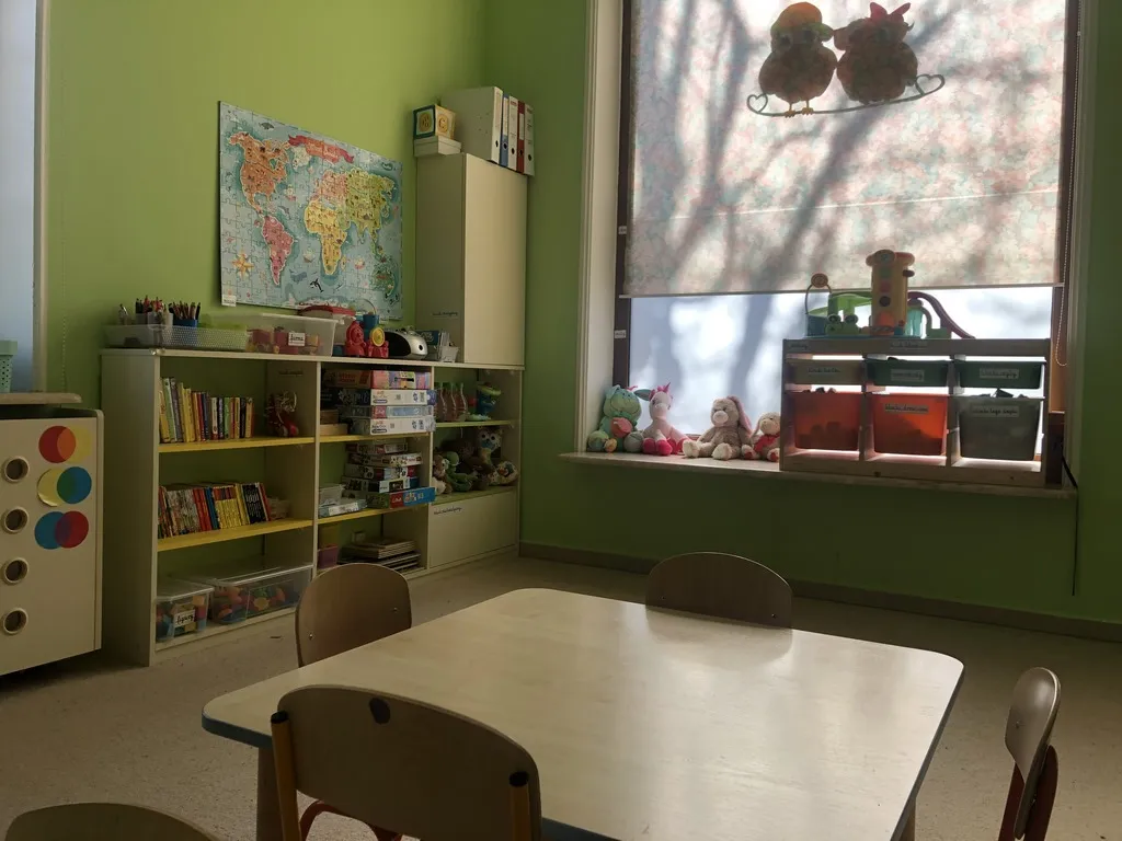 Green classroom with a world map and shelves of toys